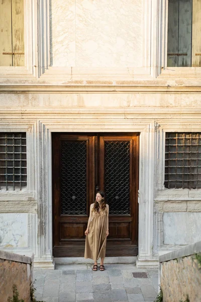 Mulher grávida em vestido olhando para longe perto de construção na rua em Veneza — Fotografia de Stock