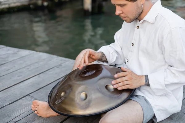 Barefoot musician playing metal hang drum on pier in Venice — Stock Photo