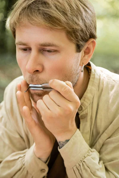 Retrato del hombre tocando el arpa judía en el bosque - foto de stock