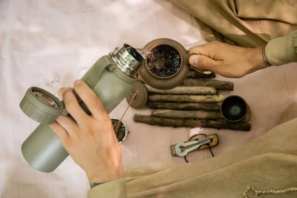 Top view of man pouring water in teapot on blanket outdoors - foto de stock