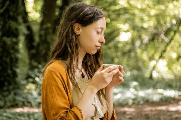 Seitenansicht einer jungen Frau mit einer Teeschale im Wald — Stockfoto