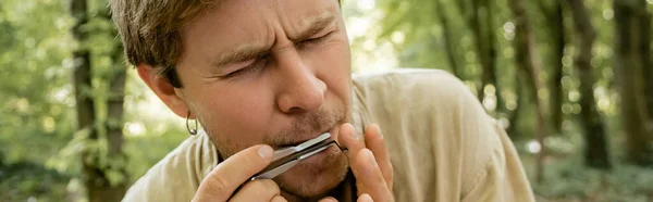 Retrato del hombre jugando vargan en el borroso bosque de verano, bandera — Stock Photo