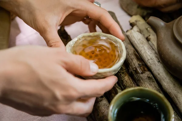 Cropped view of woman holding bowl near wooden board during tea ceremony outdoors — Stock Photo