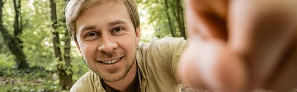 Улыбающийся человек смотрит в камеру в летнем лесу, баннер — стоковое фото
