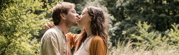 Vista lateral de la mujer morena besando marido en el bosque de verano, pancarta - foto de stock