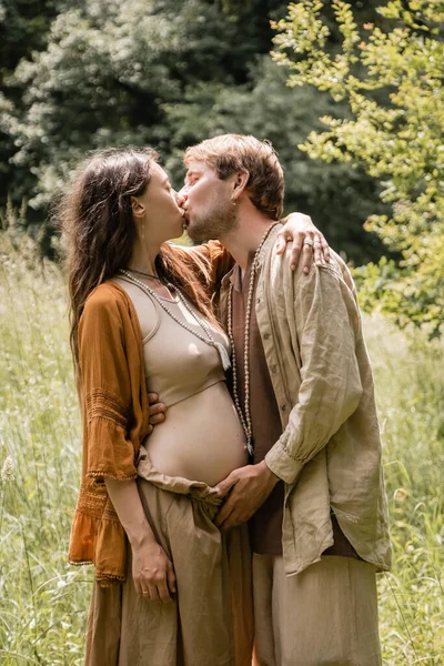 Vue latérale de l'homme embrassant femme enceinte dans la forêt d'été — Photo de stock