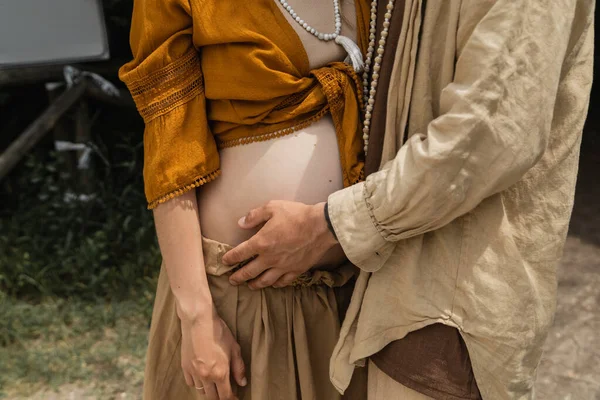 Обрезанный вид мужчины, трогающего беременную жену в лесу — стоковое фото