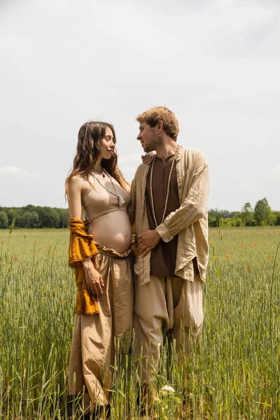 Pregnant woman looking at husband in summer field — Foto stock