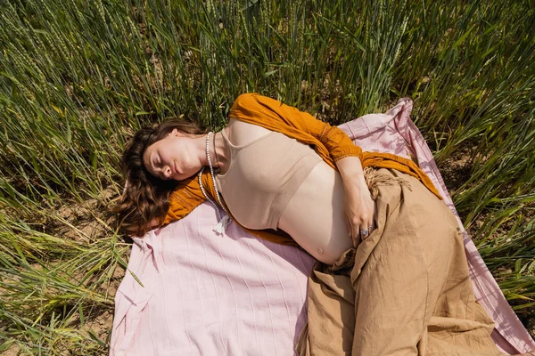 Top view of pregnant woman lying on blanket in field — Photo de stock