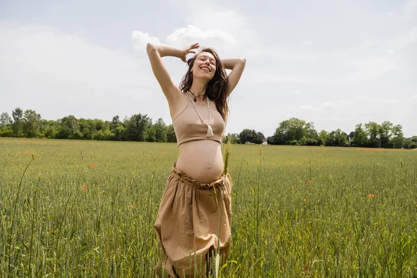 Счастливая беременная женщина стоит в поле с шипами — стоковое фото