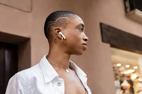 Vista lateral de la elegante mujer afroamericana usando auriculares en la calle urbana de Treviso - foto de stock