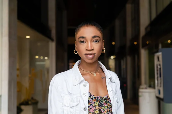 Portrait d'une femme afro-américaine élégante regardant une caméra sur une rue urbaine floue à Trévise — Photo de stock