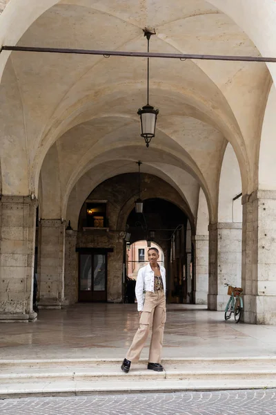 Smiling african american woman posing near old building on urban street in Treviso — Stock Photo