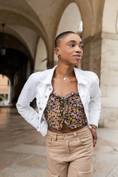 Elegante donna afroamericana in giacca bianca che guarda lontano sulla strada urbana di Treviso — Foto stock