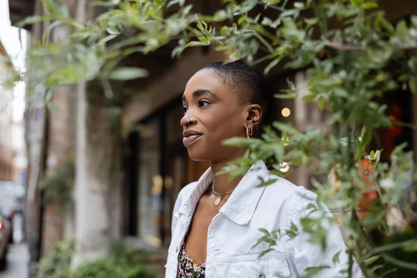 Trendy short haired african american woman standing on blurred city street — Stock Photo