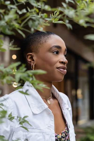 Porträt einer stilvollen afrikanisch-amerikanischen Frau, die im Freien neben einem verwischten Baum steht — Stockfoto