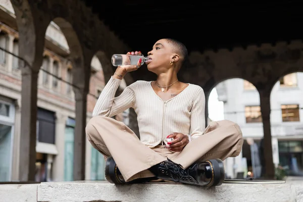 Vista laterale del turista afroamericano che beve acqua vicino al taccuino sulla strada cittadina di Treviso — Foto stock