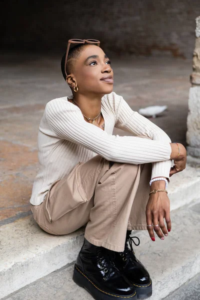 Stylish african american woman with sunglasses sitting on stairs outdoors — Stock Photo