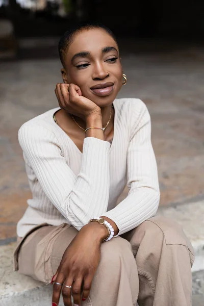 Femme afro-américaine à la mode tenant la main près de la joue sur la rue urbaine — Photo de stock