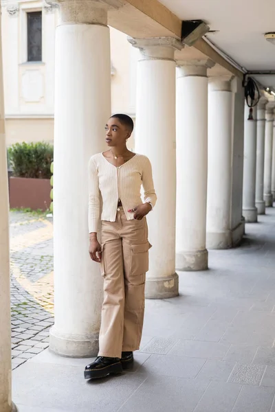 Fashionable short haired african american woman standing near column of building outdoors in Italy — Stock Photo