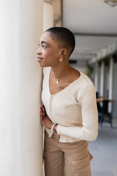 Elegante donna afroamericana in piedi vicino alla colonna sulla strada urbana in Italia — Foto stock