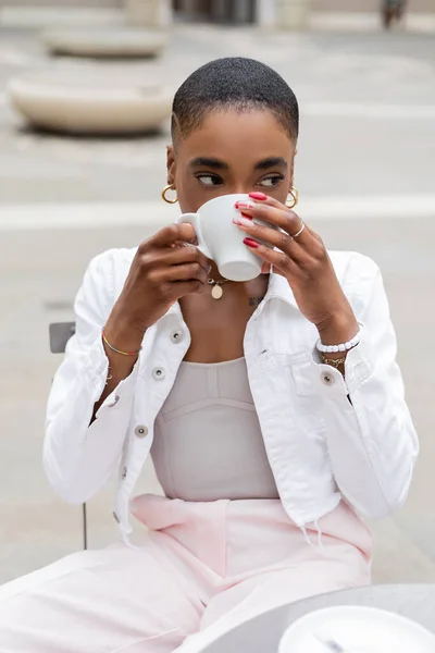 Fashionable african american tourist drinking coffee in outdoor cafe — Stock Photo