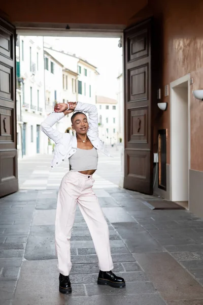 Smiling fashionable african american woman closing eyes on urban street in Treviso — Stock Photo