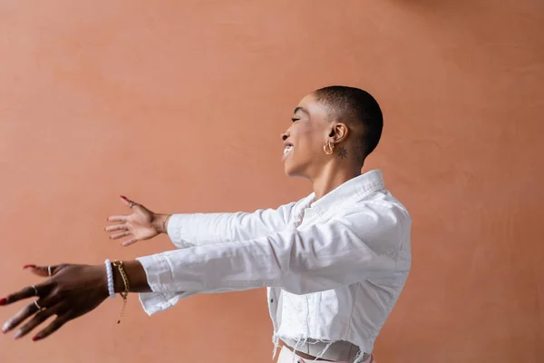 Vue latérale de la femme afro-américaine souriante étendant les mains à l'extérieur — Photo de stock