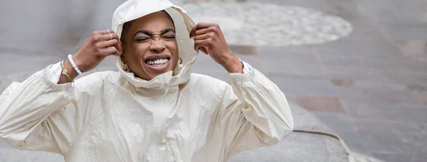 Модная африканская женщина в плаще улыбается на городской улице, баннер — стоковое фото