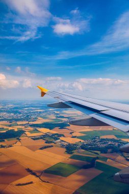 Uçak pencereleri yerin üzerinde, simgesel yapının üzerinde bir görünüme sahiptir. Bir uçak penceresinden, tarım arazileri ve tarlaların üzerinde uçan bir kanadın üzerinden bakın. Uçan uçak penceresinden görünüm.