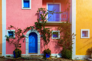 Assos, Kefalonia adasında çiçekli Yunan evleri olan geleneksel cadde. Assos köyündeki geleneksel renkli Yunan evleri. Çiçek açan fuşya çiçekleri. Kefalonia Adası, Yunanistan