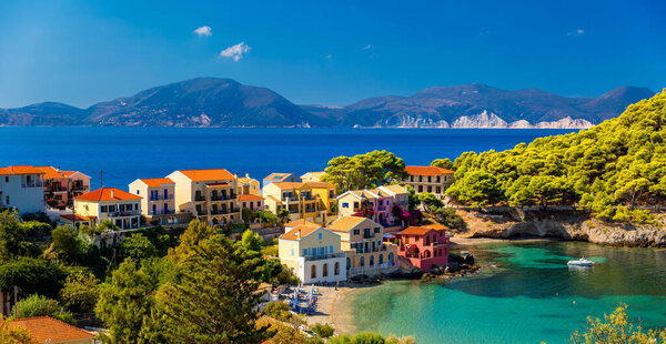 Бирюзовый залив в Средиземном море с красивыми красочными домами в деревне Ассос в Кефалонии, Греция. Town of Assos with colorful houses on the medanean sea, Greece. 
