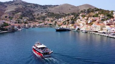 Symi (Simi) ada limanı, klasik gemi yatları, ada tepelerindeki evler, Ege Körfezi manzarası. Yunanistan adaları Rodos adasından tatil turları düzenliyor. Symi, Yunanistan, Dodecanese.