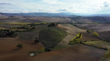Tanınmış Toskana manzarası tahıl tarlaları, selvi ağaçları ve gün batımında tepelerde evler. Tuscany, İtalya ve Avrupa 'da kıvrımlı yolu olan yaz kırsal arazisi