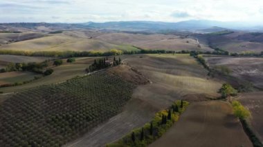 Tanınmış Toskana manzarası tahıl tarlaları, selvi ağaçları ve gün batımında tepelerde evler. Tuscany, İtalya ve Avrupa 'da kıvrımlı yolu olan yaz kırsal arazisi