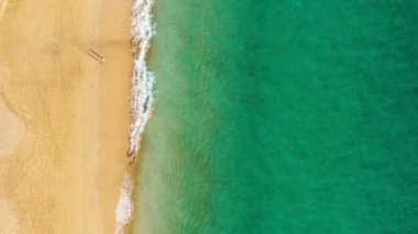 Fuerteventura Adası, İspanya, Kanarya Adaları 'nda turkuaz suyu olan bir sahil. Kum plajının havadan görünüşü, okyanus dokusunun arka plan döngüsü, İHA ile deniz dalgalarının yukarıdan aşağı görüntüsü. Fuerteventura, İspanya.