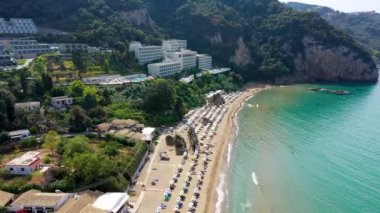 Yunanistan 'ın Korfu adasındaki Agios Gordios egzotik plajı. Agios Gordios plajı, Korfu adası, Yunanistan. Agios Gordios plajının panoramik manzarası, kumlu deniz kıyıları, plaj şemsiyeleri ve şezlonglar..