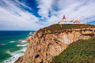 Cabo da Roca 'daki deniz feneri. Portekiz 'in güzel bir yaz gününde Sintra' da Atlantik Okyanusu kıyısındaki kayalıklar ve kayalar. Cabo da Roca, Portekiz. Atlantik Okyanusu üzerindeki deniz feneri ve kayalıklar.