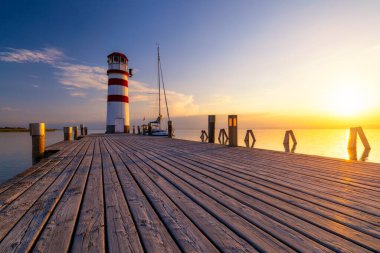 Neusiedl Gölü 'ndeki deniz feneri, Podersdorf am See, Burgenland, Avusturya. Avusturya 'da gün batımında deniz feneri. Podersdorf 'ta deniz feneri olan ahşap iskele Avusturya' da Neusiedl Gölü üzerinde.