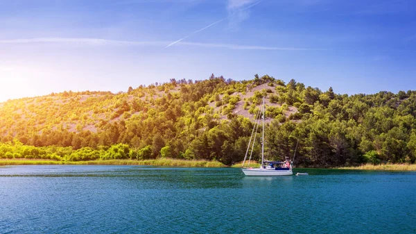 Sailboat in the sea in the evening sunlight with mountains background, luxury summer adventure, active vacation in Mediterranean sea, Croatia. Sailing ship luxury yacht with white sails in the Sea.