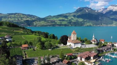 Günbatımında İsviçre kantonundaki Bern kantonunda bulunan Thun Gölü kıyısındaki Spiez Kilisesi ve Kalesi 'nin hava panoramik manzarası, Spiez, İsviçre. İsviçre, Bern kantonunda Thun Gölü 'ndeki Spiez Şatosu.