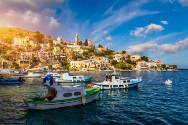 Symi (Simi) ada limanı, klasik gemi yatları, ada tepelerindeki evler, Ege Körfezi manzarası. Yunanistan adaları Rodos adasından tatil turları düzenliyor. Symi, Yunanistan, Dodecanese.