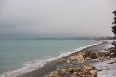 Abhazya 'da kışın Karadeniz. Yeşil ağaçlar, kar ve deniz aynı anda