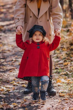 Anne ve kızı sonbahar ormanlarında oynuyorlar.