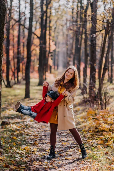 Mom and daughter play in an autumn forest