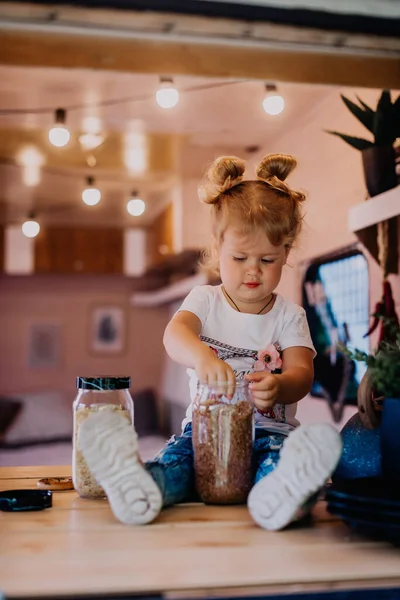 Küçük kız kampa mısır gevreği serpiyor.