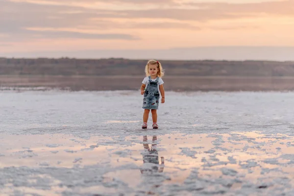 Little girl meets sunset on firth kuyalnik when it's coast is white because of the salt