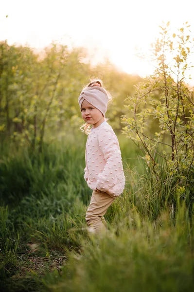Little girl have fun in a hight green grass in the sunset