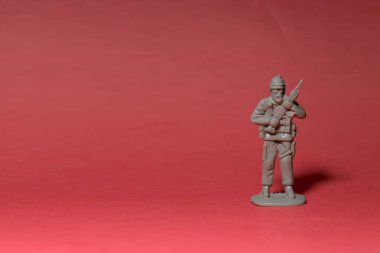 Kolları kırmızı arka planda minyatür oyuncak asker.
