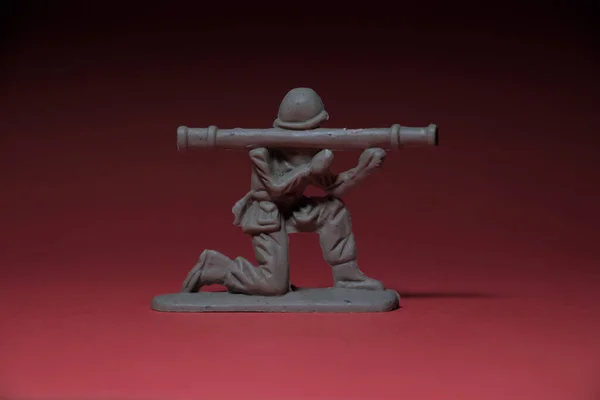 Miniature toy soldier with weapon in hand, reddish background